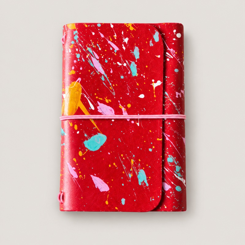 Red leather journal with colorful paint splatters