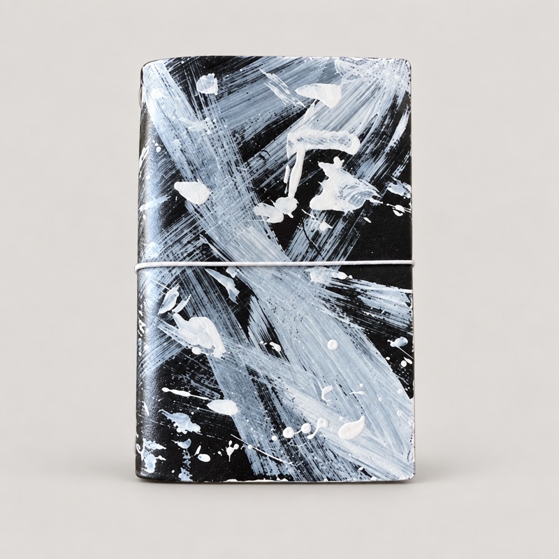 Black leather journal with white and gray painted brush strokes and splatters
